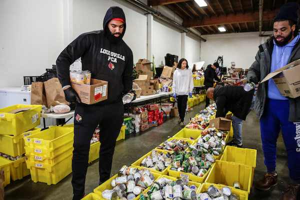 Jared Goldwire, of Tacoma, a defensive end on the University of Louisville football team, and Robert Christopher III of Seattle, organize food donations at the Emergency Feeding Program of Seattle and King County to hand out at a drive-through pick up, organized by last name on specific days of the week, amid the coronavirus (COVID-19) outbreak, in Renton, Washington, U.S. March 16, 2020. REUTERS/Jason Redmond - RC2BLF92B9IL