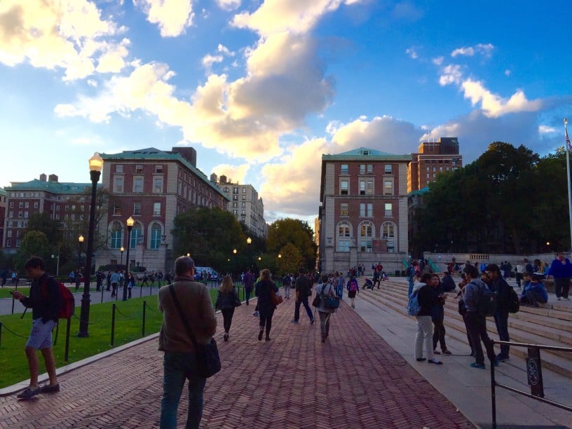 A picture of students walking through Columbia University's campus in New York City, with a mid-afternoon blue sky overhead.