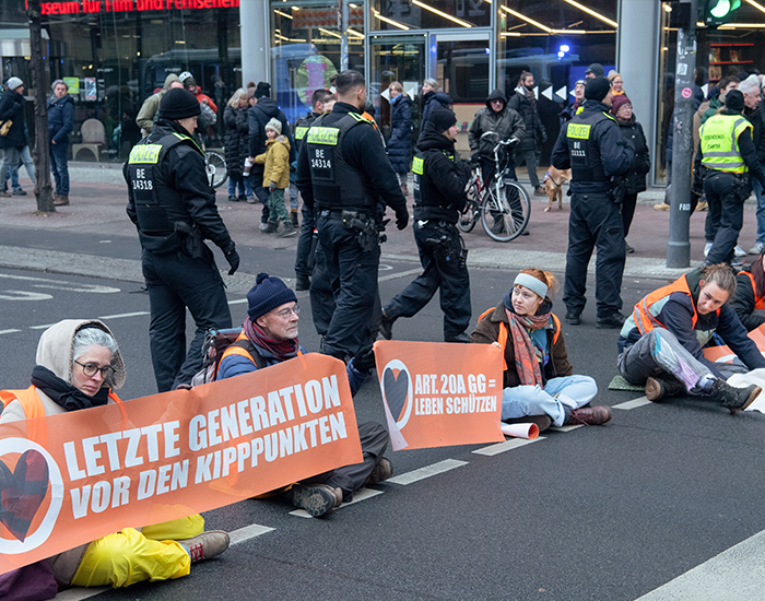 Members of the environmental group "Last Generation" block the street at Potsdamer Platz. Some other activists had previously invited passers-by to talk over tea and pastries a few 100 meters away.