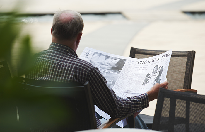 man sits at a cafe reading local newspaper