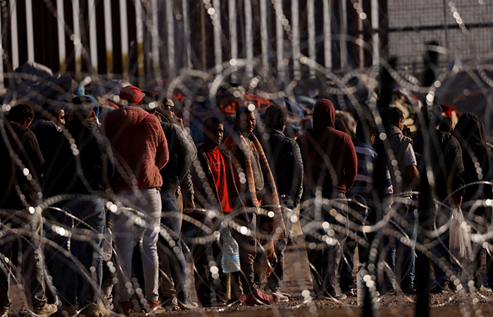 Migrants stand near the border wall after having crossed the U.S.-Mexico border to turn themselves in to U.S. Border Patrol agents, after the lifting of COVID-19 era Title 42 restrictions that have blocked migrants at the border from seeking asylum since 2020, as seen from Ciudad Juarez, Mexico May 12, 2023. REUTERS
