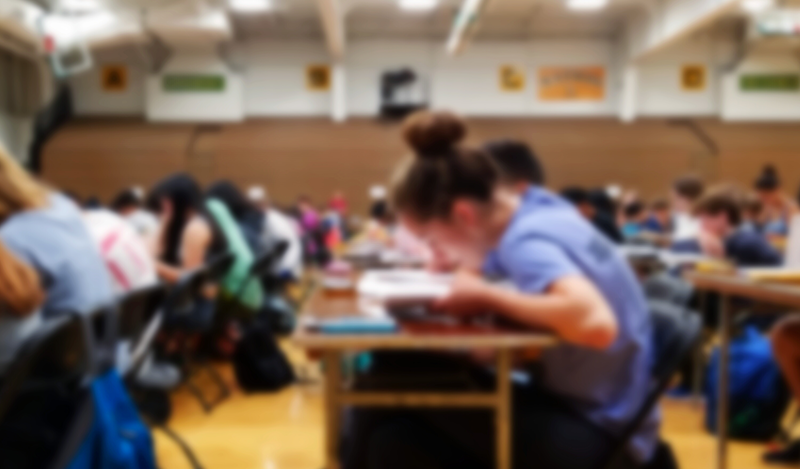 A blurred image of many students taking an exam at their desks